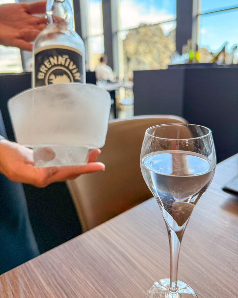 Our server holding a bottle of Brennevin surrounded by a cube of ice, and pour into a glass beside it
